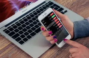 Photo of someone using their mobile device with a laptop in the background